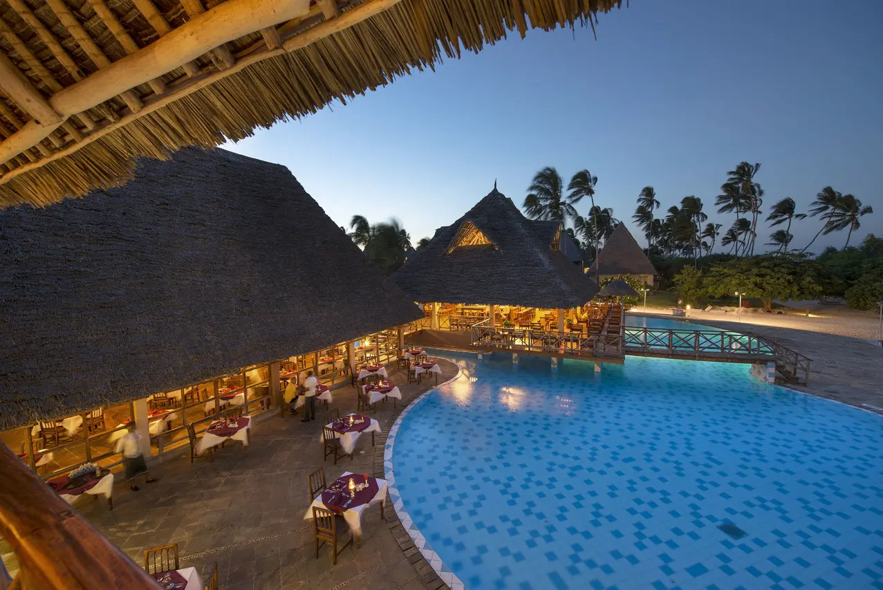 Piscina e restaurante iluminados à noite no Neptune Pwani Beach Resort & Spa