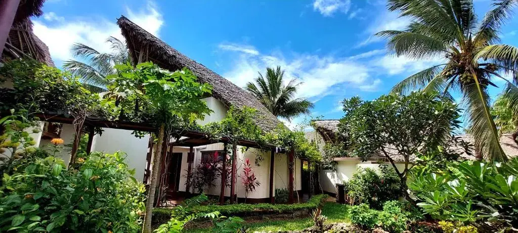 Edifícios de cobertura em colmo entre os jardins do Kena Beach Hotel, em Matemwe