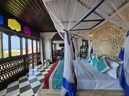 Quarto do Dhow Palace Hotel com cama de dossel em madeira entalhada e chão axadrezado
