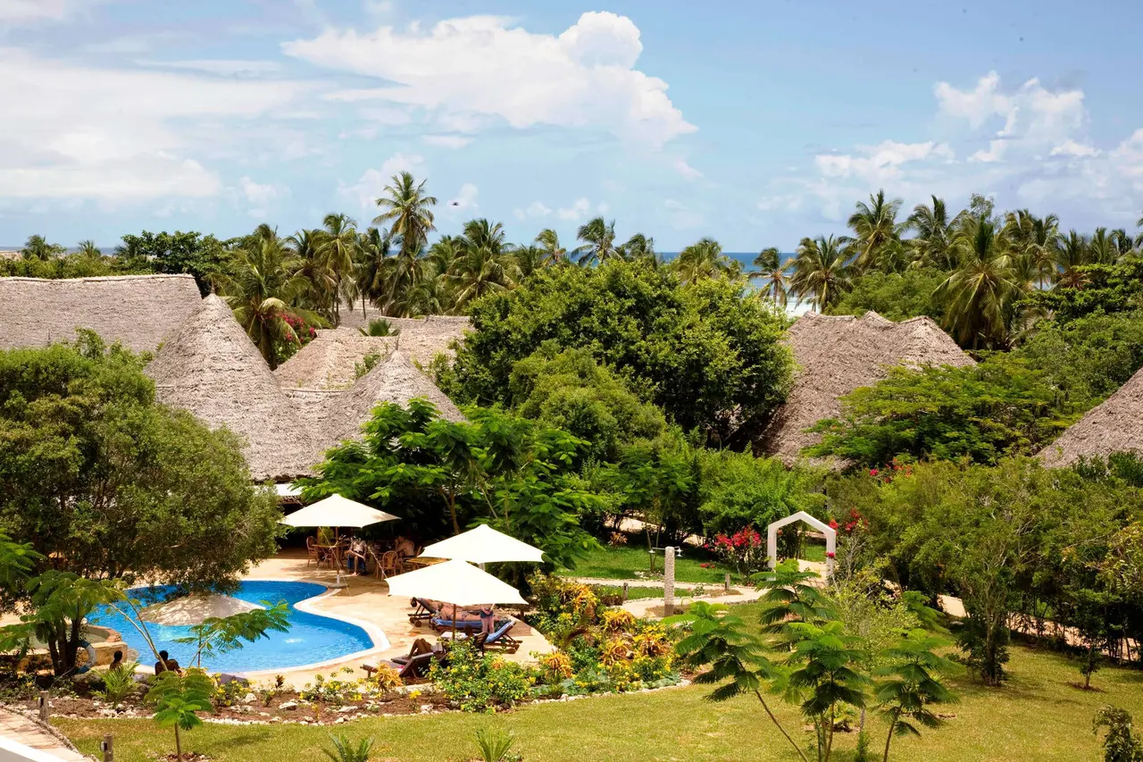 Jardins e piscina do Bluebay Beach Resort & Spa entre edifícios de cobertura em colmo