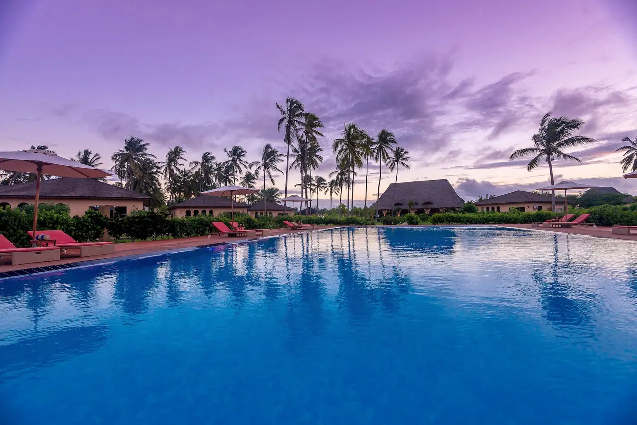 Piscina do The Sands Beach Resort Zanzibar rodeada por espreguiçadeiras e bungalows