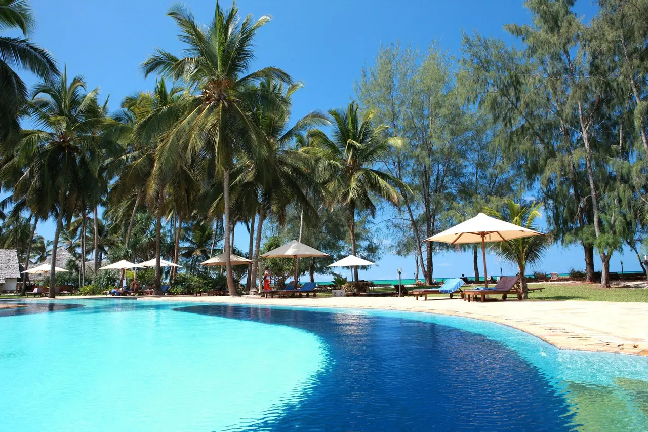 Piscina do Bluebay Beach Resort & Spa com palmeiras e espreguiçadeiras junto ao mar