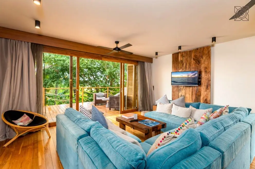 Sala de uma suite do Zuri Zanzibar com sofás e terraço entre a vegetação