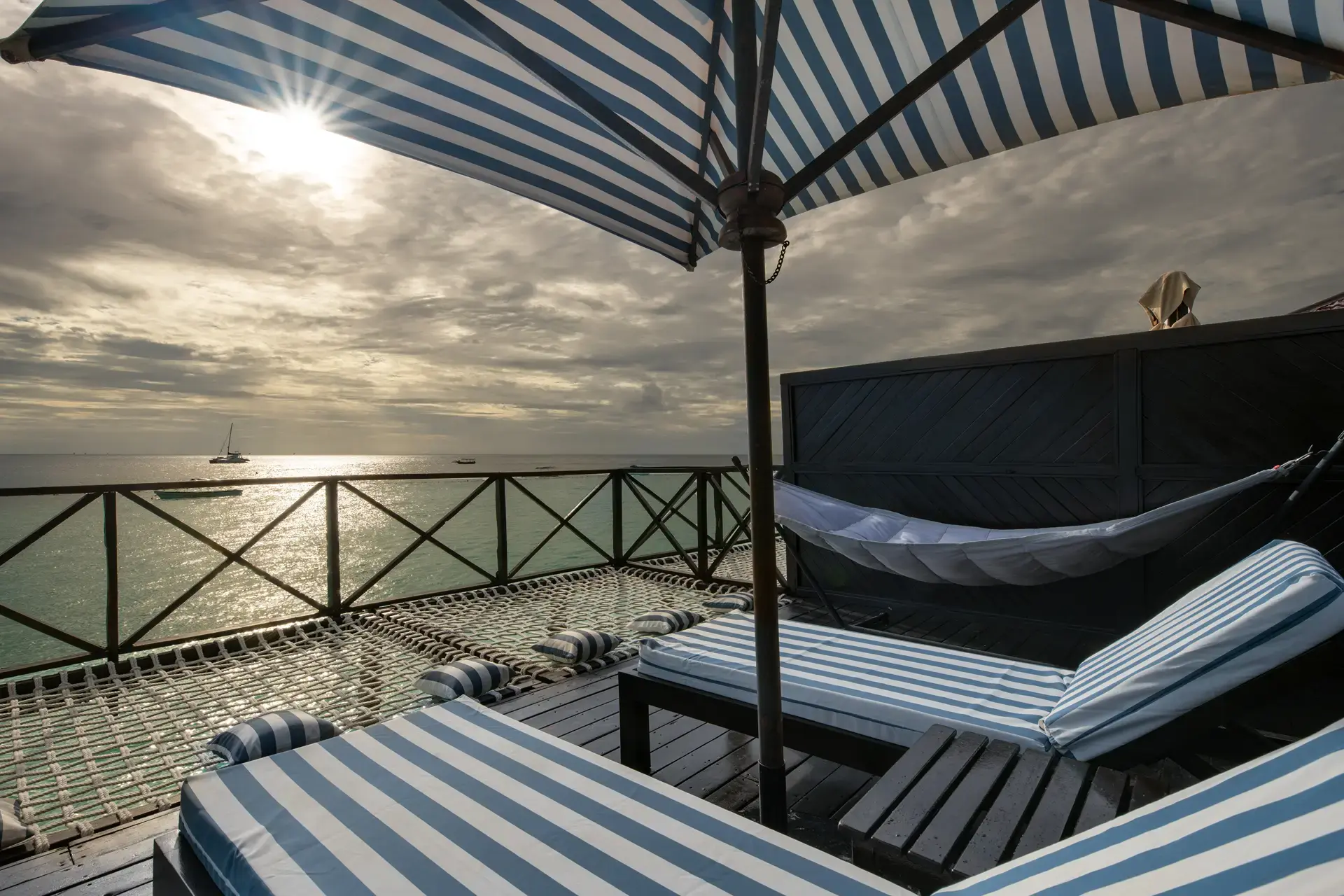 Varanda de um cottage do The Z Hotel com espreguiçadeiras e rede sobre o mar